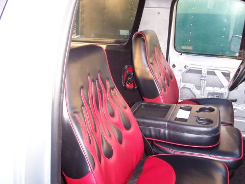 1990 Ford Bronco - The interior of a vehicle features custom seats with red flame accents and a central console with multiple cup holders.