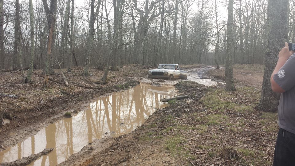 White 1979 Ford Bronco driving through a muddy trail