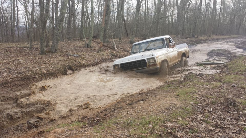 White pickup truck stuck in mud, front grille visible