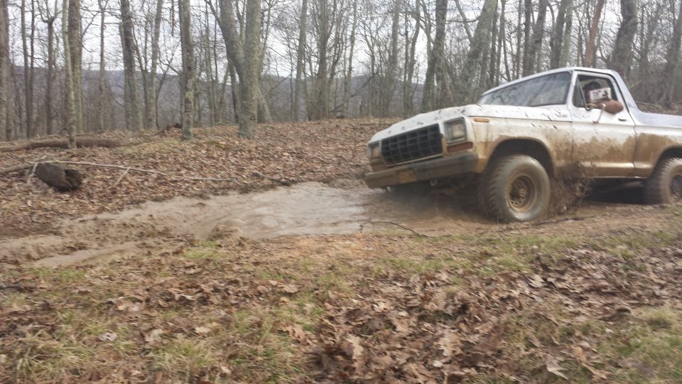 1979 Ford Bronco driving through mud, 3q-front view