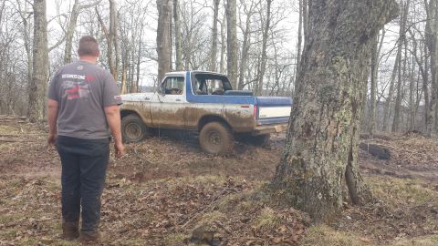 1979 Ford Bronco - A muddy 1979 Ford Bronco navigates a wooded trail.