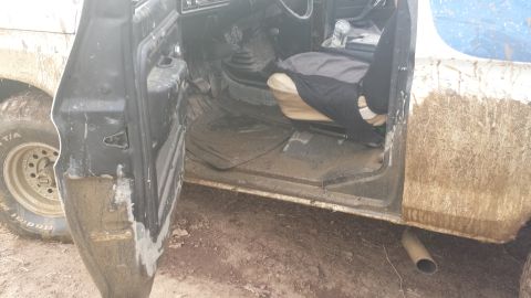 1979 Ford Bronco - The interior of a muddy 1978 Ford Bronco is visible with the driver's door ajar.
