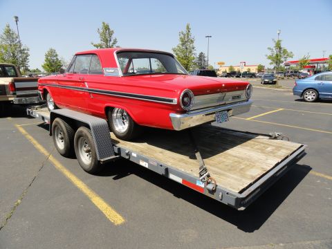 1964 Ford Fairlane - A red 1964 Ford Fairlane coupe is loaded onto a trailer in a parking lot.