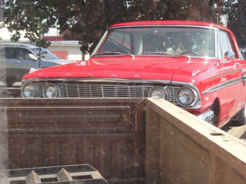 1964 Ford Fairlane - This red 1964 Ford Fairlane features a distinctive chrome grille and dual headlights, visible from the front.