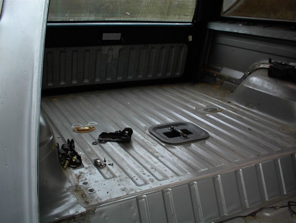 Empty truck bed with some parts on the floor. Some water damage visible