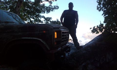 1979 Ford Bronco - A 1979 Ford Bronco is parked on a rocky incline with a person standing beside it.