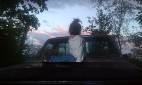 1979 Ford Bronco - A person sits on the hood of a truck, silhouetted against a colorful twilight sky.