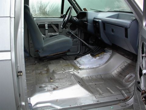 1990 Ford Bronco - The interior of a 1990 Ford Bronco shows gray seats and a bare metal floor with visible wear.