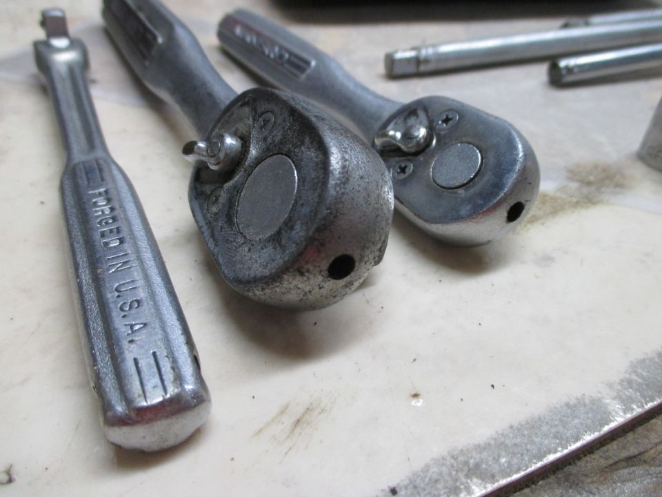 Three metal ratchet wrenches, one with "FORGED IN U.S.A." visible, on a light-colored surface
