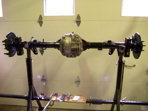 1999 Mercury Grand Marquis - A rear axle assembly is mounted on stands in front of a garage door.
