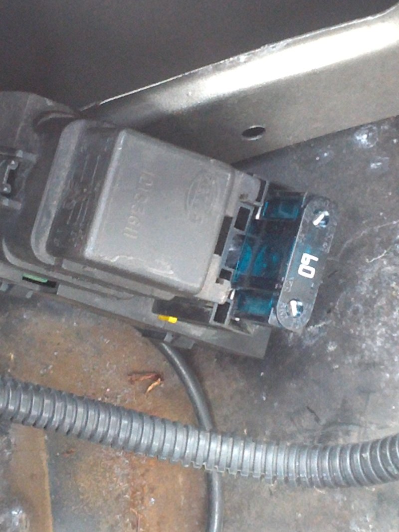 Close-up of a gray automotive relay and a fuse holder with blue fuses. Some text is visible on the relay and fuses