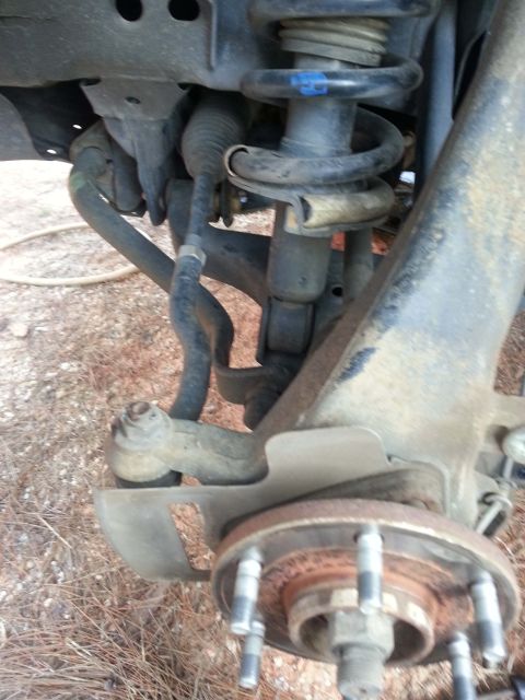 2006 Nissan Titan - Close-up view of the front suspension system of a vehicle, focusing on the shock absorber and steering linkage.