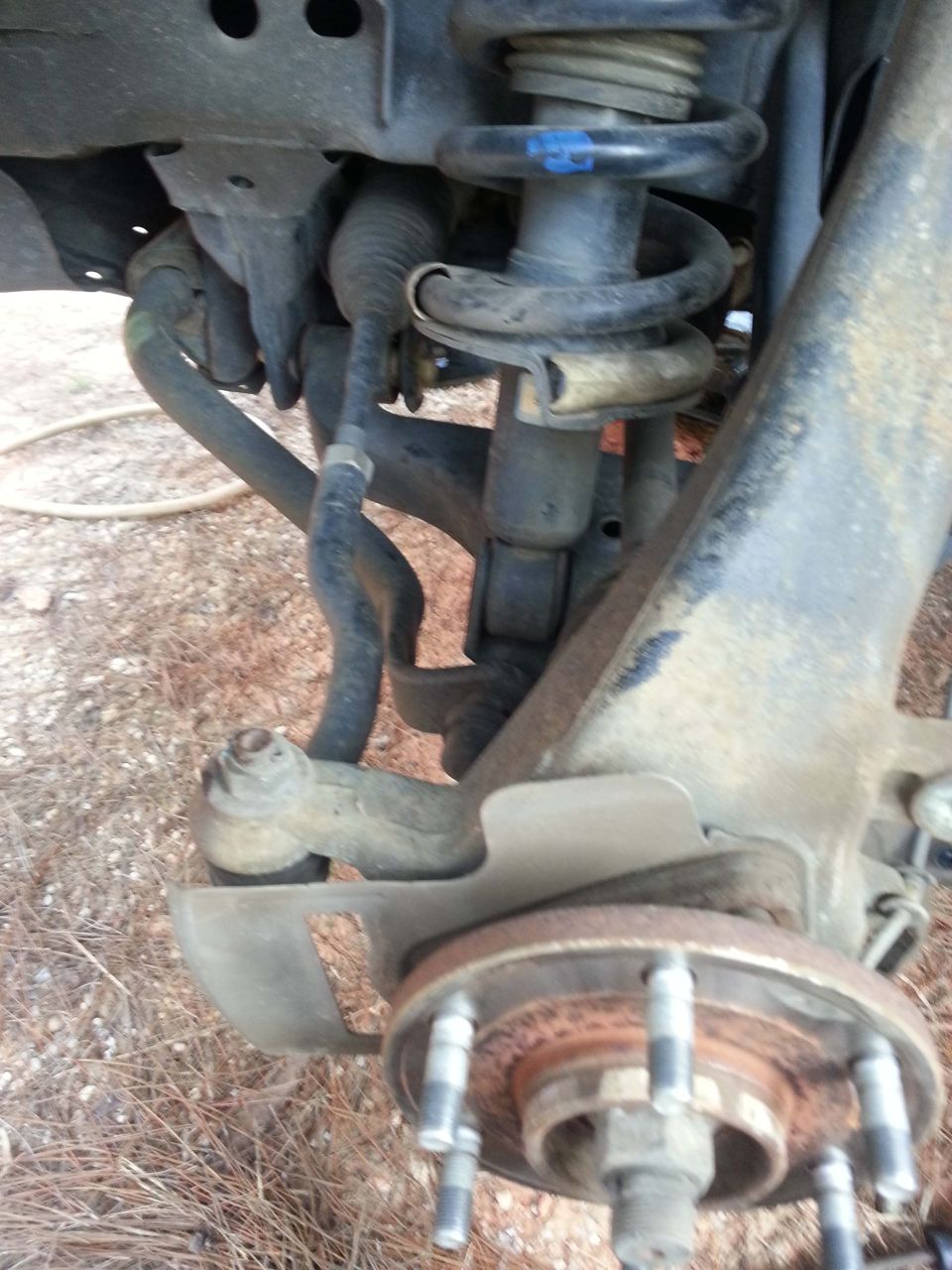 Front suspension part of a 2004 Nissan Titan, showing the brake rotor, tie rod end, and coilover shock