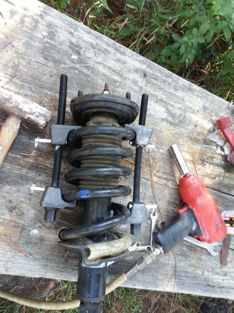 2006 Nissan Titan - Strut assembly being worked on with a spring compressor tool and an air impact wrench.