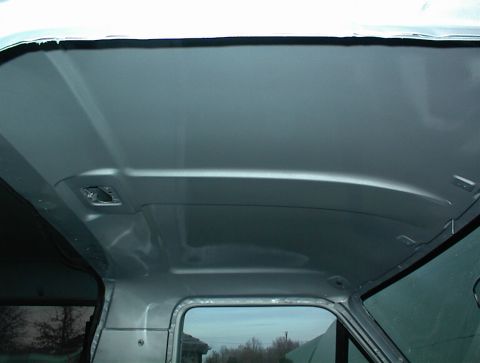 1990 Ford Bronco - The interior roof of a vehicle, painted silver, reveals its structural contours and mounting points.