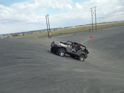 2005 Jeep Wrangler - A Jeep Wrangler navigates a sandy incline under a partly cloudy sky.