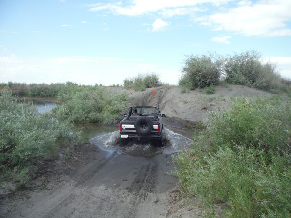 Black convertible SUV driving through water on a dirt path