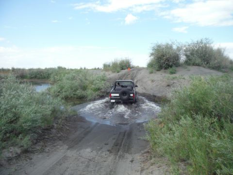2005 Jeep Wrangler - A black 2005 Jeep Wrangler navigates through a shallow water crossing on a dusty trail.