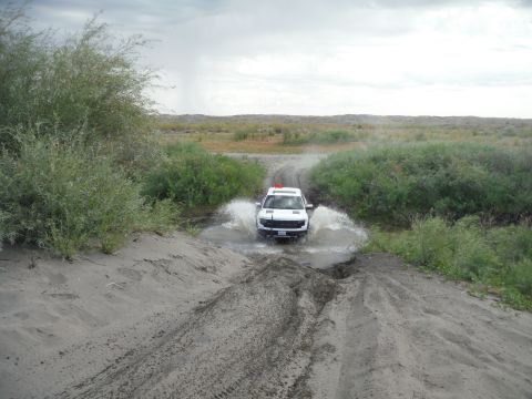 2005 Jeep Wrangler - SUV navigates a muddy water crossing on an off-road trail.