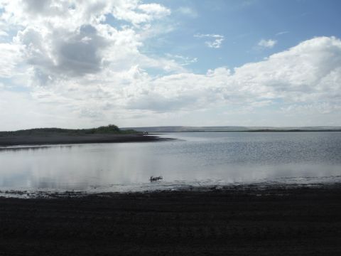 2005 Jeep Wrangler - Distant vehicles are visible on the shore of a large body of water under a partly cloudy sky.