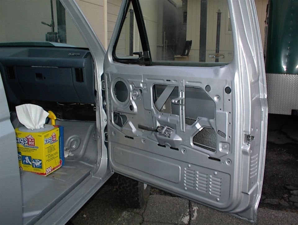 Silver vehicle interior, driver's door open, showing door panel removed. Box of rags on floor