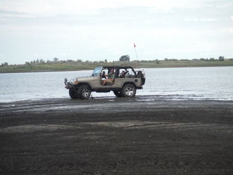2005 Jeep Wrangler - 2005 Jeep Wrangler parked on the shore of a lake with people inside.