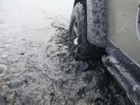 2005 Jeep Wrangler - A Jeep Wrangler navigates through a muddy terrain, kicking up water and mud.