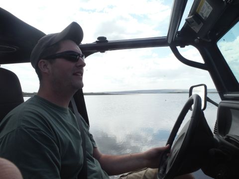 2005 Jeep Wrangler - Driver's perspective inside a Jeep Wrangler, looking out at a calm lake under a cloudy sky.