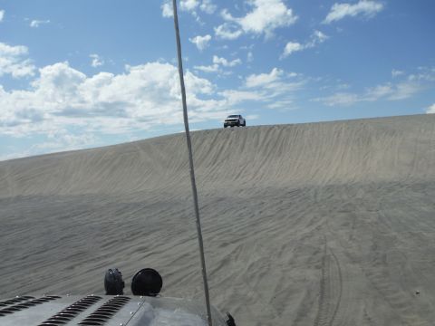 2005 Jeep Wrangler - Two vehicles navigate a sandy landscape under a partly cloudy sky.
