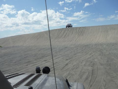 2005 Jeep Wrangler - Two SUVs navigate a sandy landscape under a partly cloudy sky.