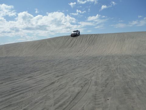 2005 Jeep Wrangler - Pickup truck navigates a sandy incline on a clear day.