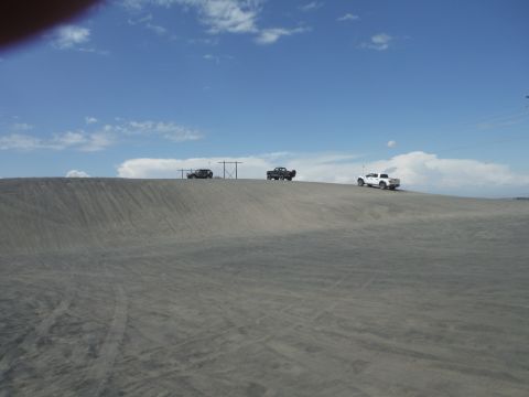 2005 Jeep Wrangler - Several off-road vehicles navigate a sandy terrain under a bright blue sky with scattered clouds.