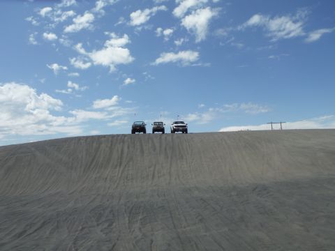 2005 Jeep Wrangler - Three SUVs are lined up on the crest of a sandy hill against a bright blue sky.