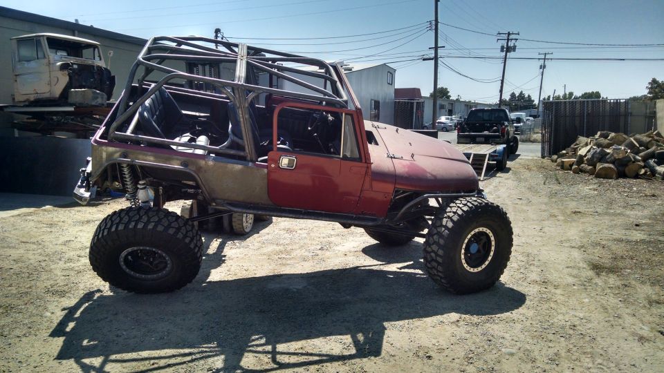 Custom Jeep CJ with roll cage and large tires, parked outside