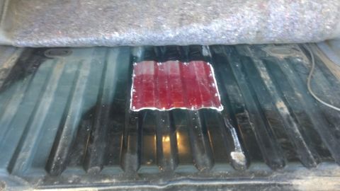 1995 Ford Bronco - A red panel has been fitted into the ribbed floor of a truck bed.