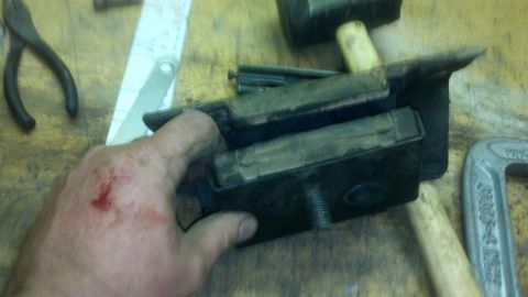 1995 Ford Bronco - A hand with a cut holds a rubber and metal part with a bolt, with tools in the background.
