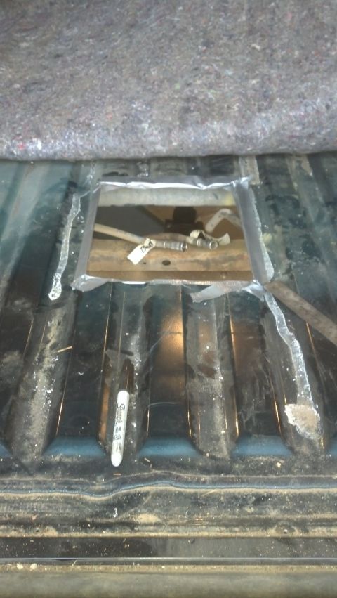 1995 Ford Bronco - Vehicle floor with a cutout revealing the fuel filler neck assembly.