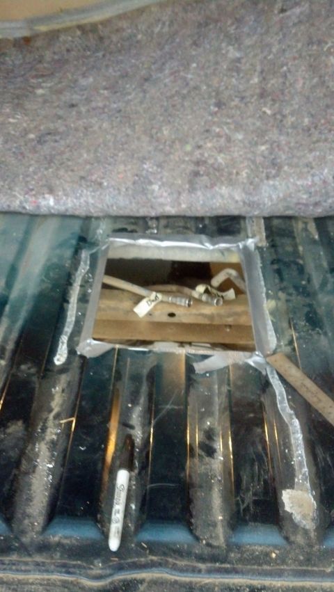 1995 Ford Bronco - A hole has been cut into the vehicle's floor, revealing fuel lines and a wooden support structure underneath.