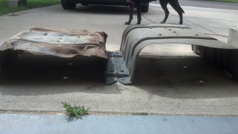 1995 Ford Bronco - Two fuel tanks, one rusty metal and one black plastic, are on a driveway.