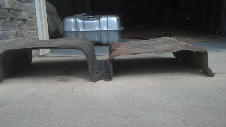 New gas tank and two old metal shields on concrete floor