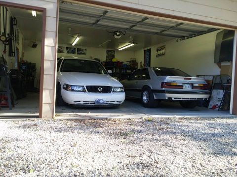 2000 Mercury Grand Marquis - Two cars, a 1987 Ford Mustang GT and a Mercury Grand Marquis, parked inside a garage.