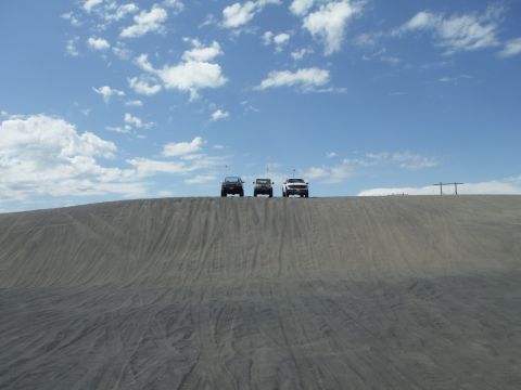 2005 Jeep Wrangler - Three SUVs are parked on top of a sand dune on a sunny day.