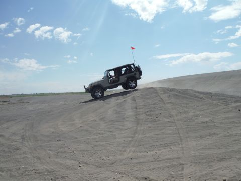 2005 Jeep Wrangler - A Jeep Wrangler navigates a sandy incline under a partly cloudy sky.