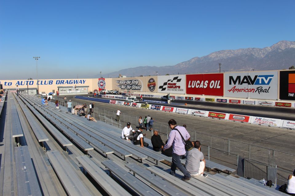 Empty aluminum grandstands at Auto Club Dragway with sponsor banners