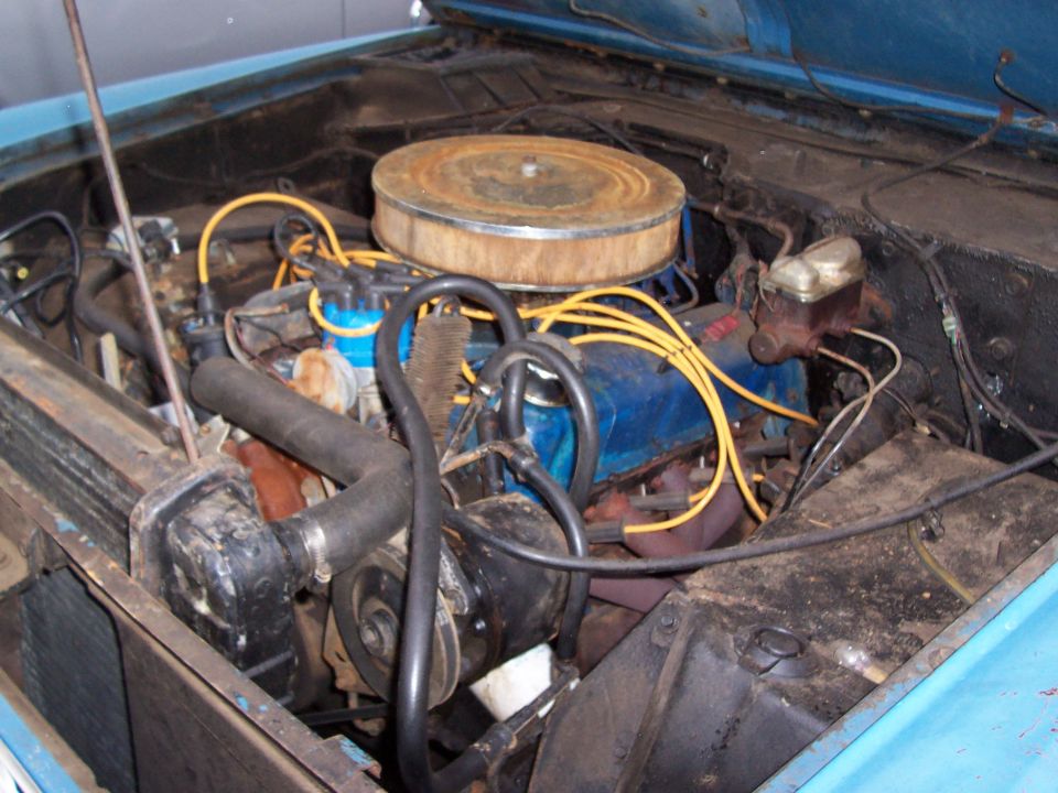 engine bay with blue engine block, yellow spark plug wires, and a rusty air cleaner