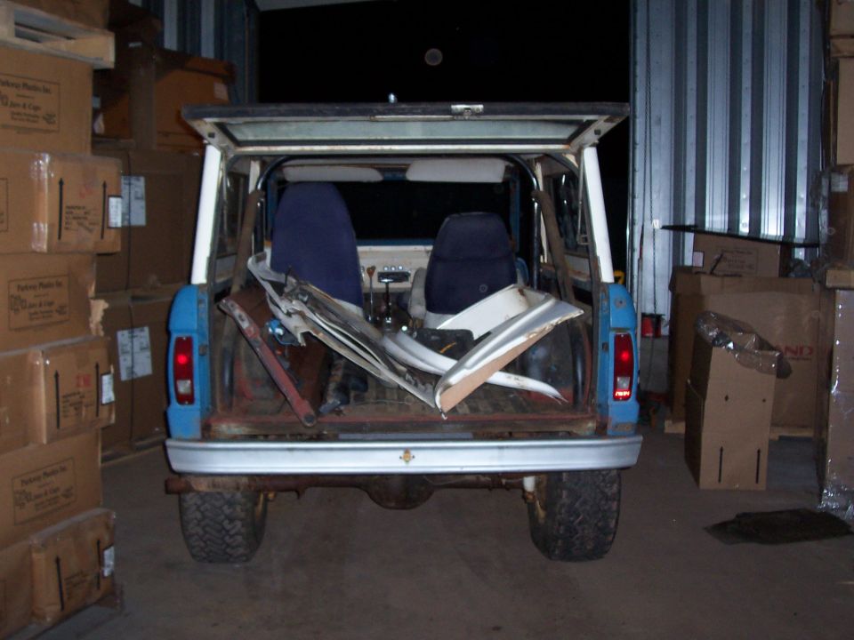 Blue SUV with open tailgate, interior visible, parts loaded in back. Appears to be a first-generation Ford Bronco