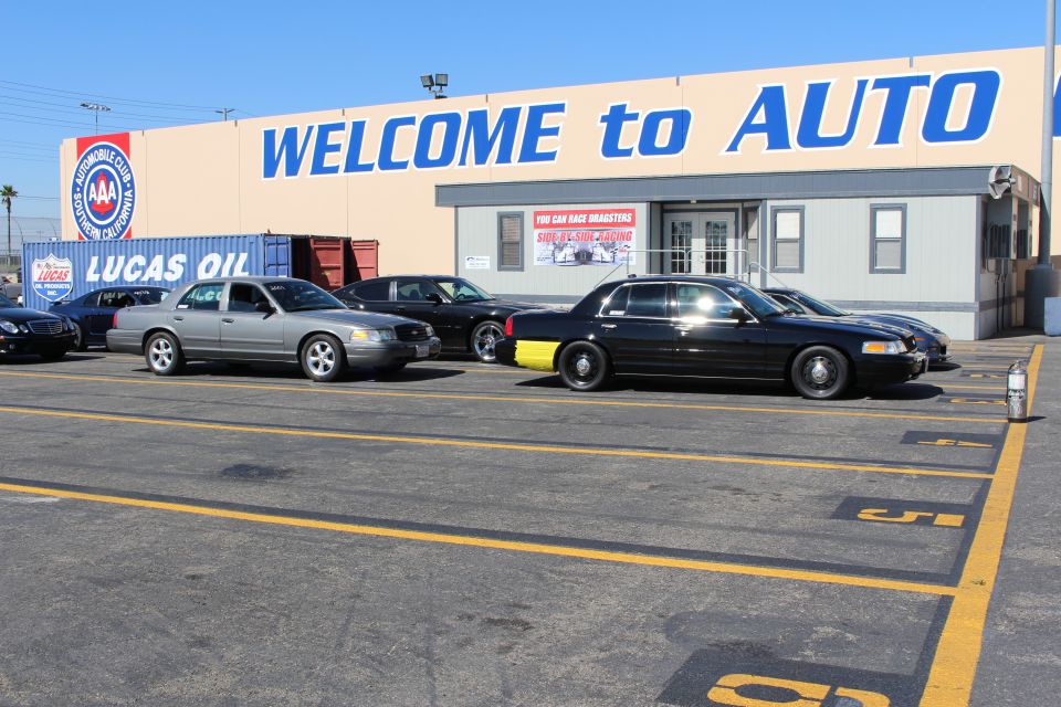 Gray and black sedans angle-parked in front of WELCOME to AUTO building