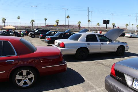 2003 Ford Crown Victoria - row of Ford Crown Victoria sedans parked in a lot, including a silver car with its hood raised and a maroon car in the foreground.