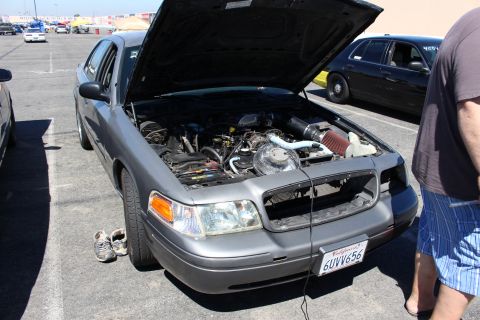 2003 Ford Crown Victoria - gray Ford Crown Victoria with its hood up revealing a turbocharged engine, California plate 6UVV656, parked at a track lot.