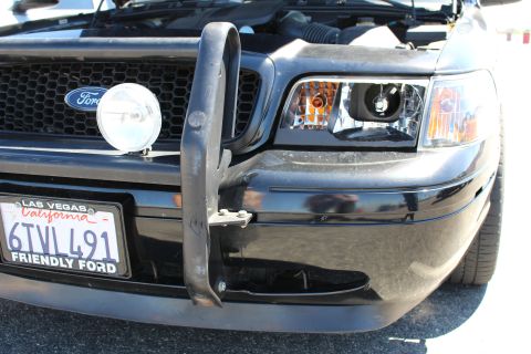 2003 Ford Crown Victoria - Front close-up of a black Ford with a push bar, auxiliary spotlight, Ford oval grille and California plate 6TVL491 in a Friendly Ford frame.